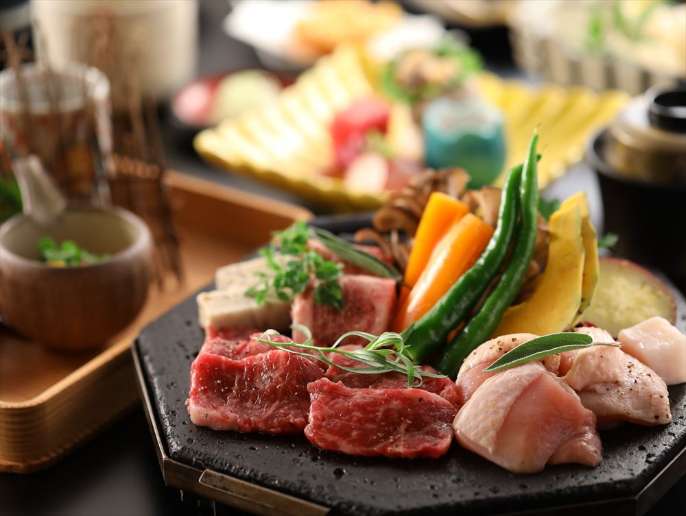 Mori No Yu Kira No Sato_Dinner (image). A Japanese kaiseki feast featuring a main course of meat grilled on lava rock.