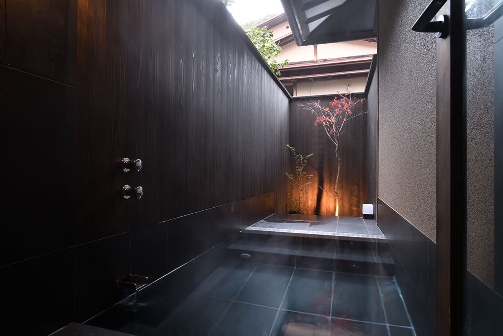 Shuzenji Hanareyado Oninosumika. A modern open-air bath to take a dip in the renowned hot spring waters and relax with trees in the alcove at your leisure.