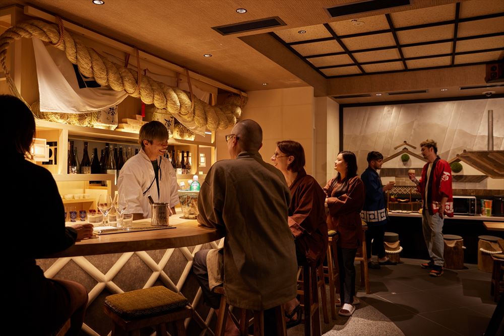 SAKE Bar Hotel 浅草。日本酒を酌み交わす。1階のSAKE BARでは吉川醸造の日本酒『雨降』シリーズをご用意しています。ご自身で枡に注いでお楽しみください。